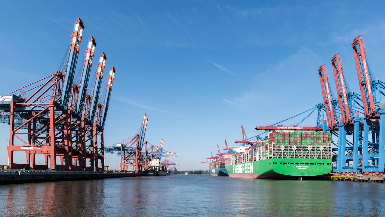 View of container ships and cranes at the busy Port of Hamburg under a clear sky.